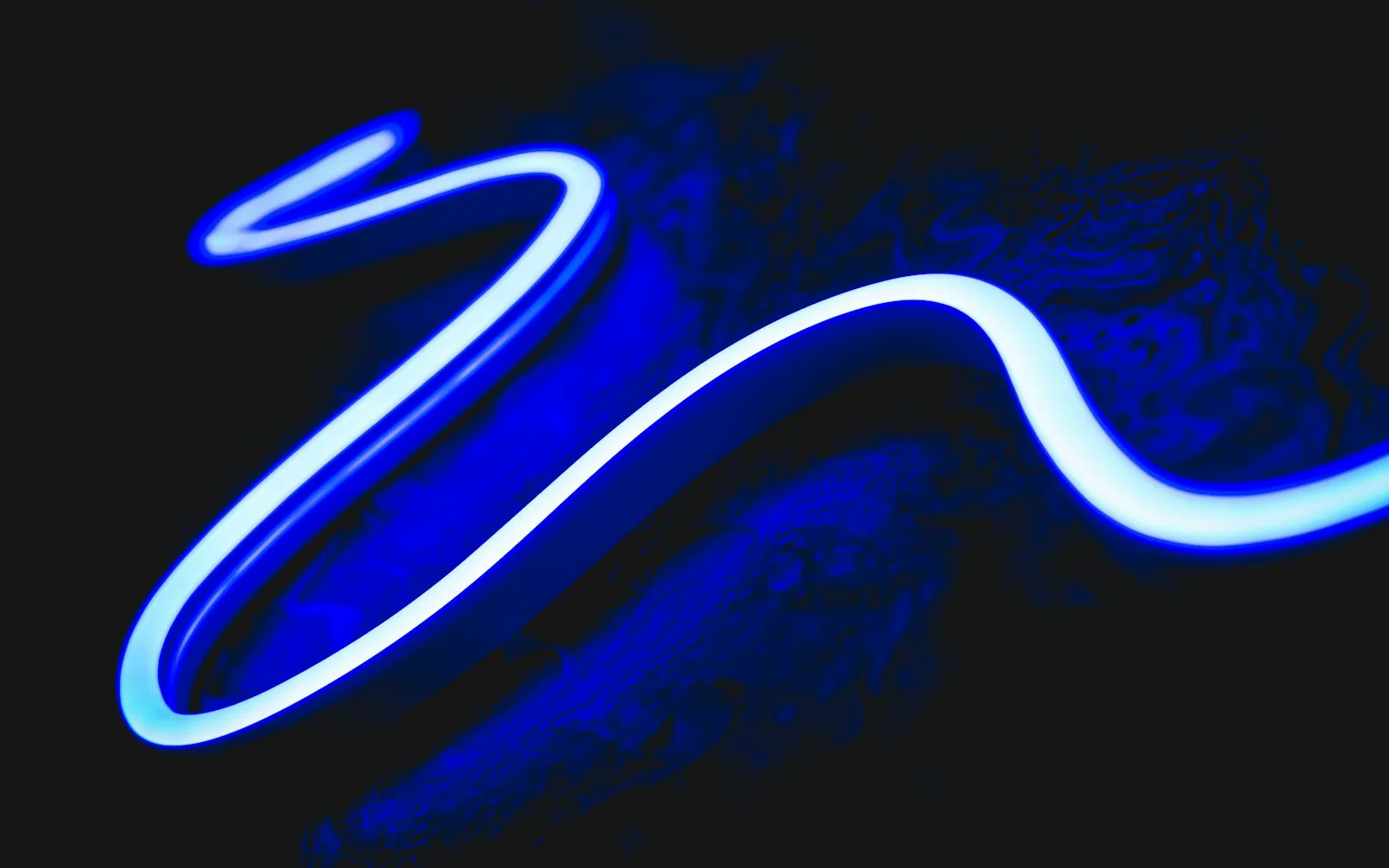 A glowing blue neon light tube curving across a dark background