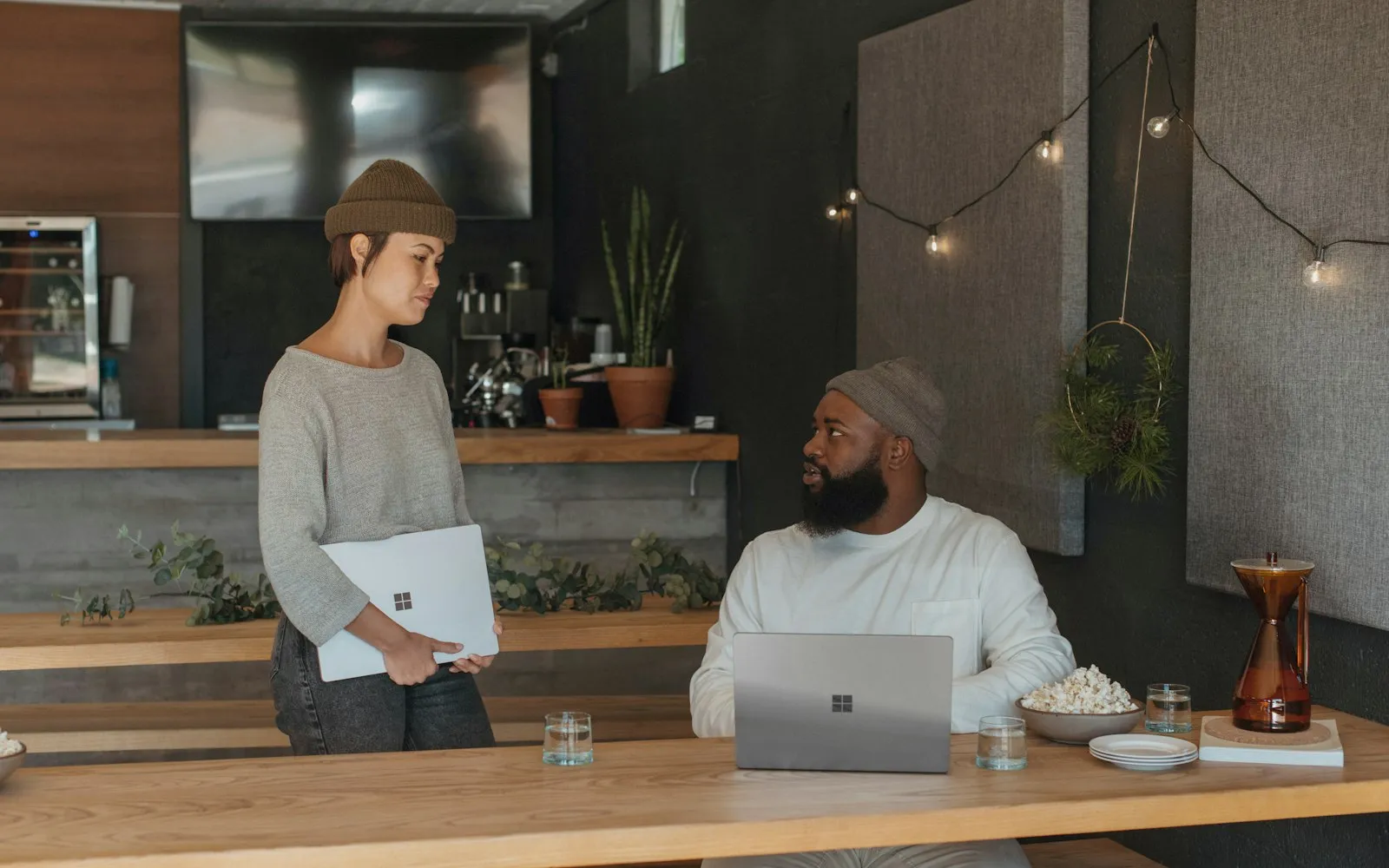 Two colleagues talking in a modern lounge, each holding a Microsoft Surface laptop