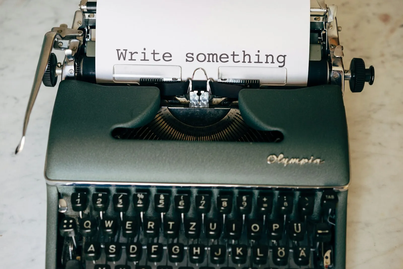 An Olympia typewriter with a sheet of paper that reads Write something