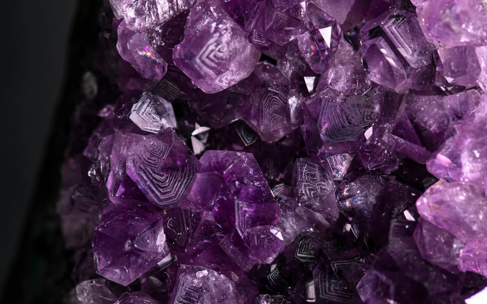 Close-up of purple amethyst crystals with visible growth patterns against a dark background
