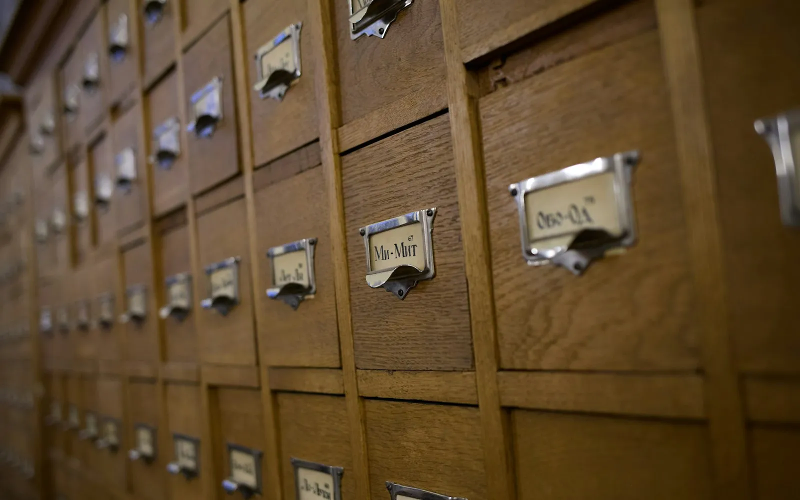 A wall of wooden library card catalogue drawers with metal label holders, suggesting sourced, cited research
